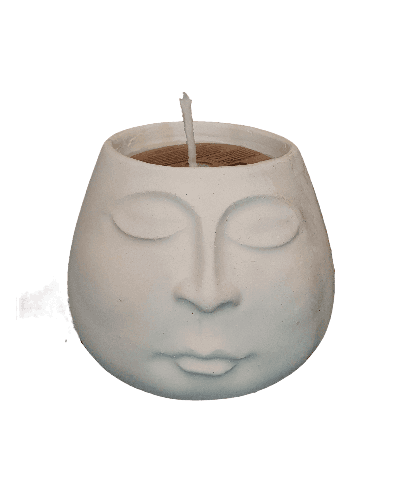 Ceramic face-shaped candle holder with a lit candle inside on a white background