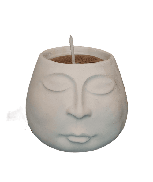 Ceramic face-shaped candle holder with a lit candle inside on a white background