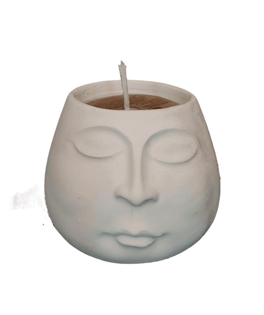 Ceramic face-shaped candle holder with a lit candle inside on a white background